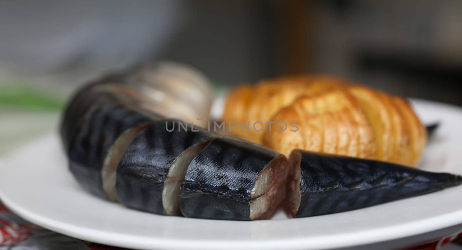 Baked golden potatoes with herring mackerel fish on a white plate. Traditional dish of English cuisine chips and fish