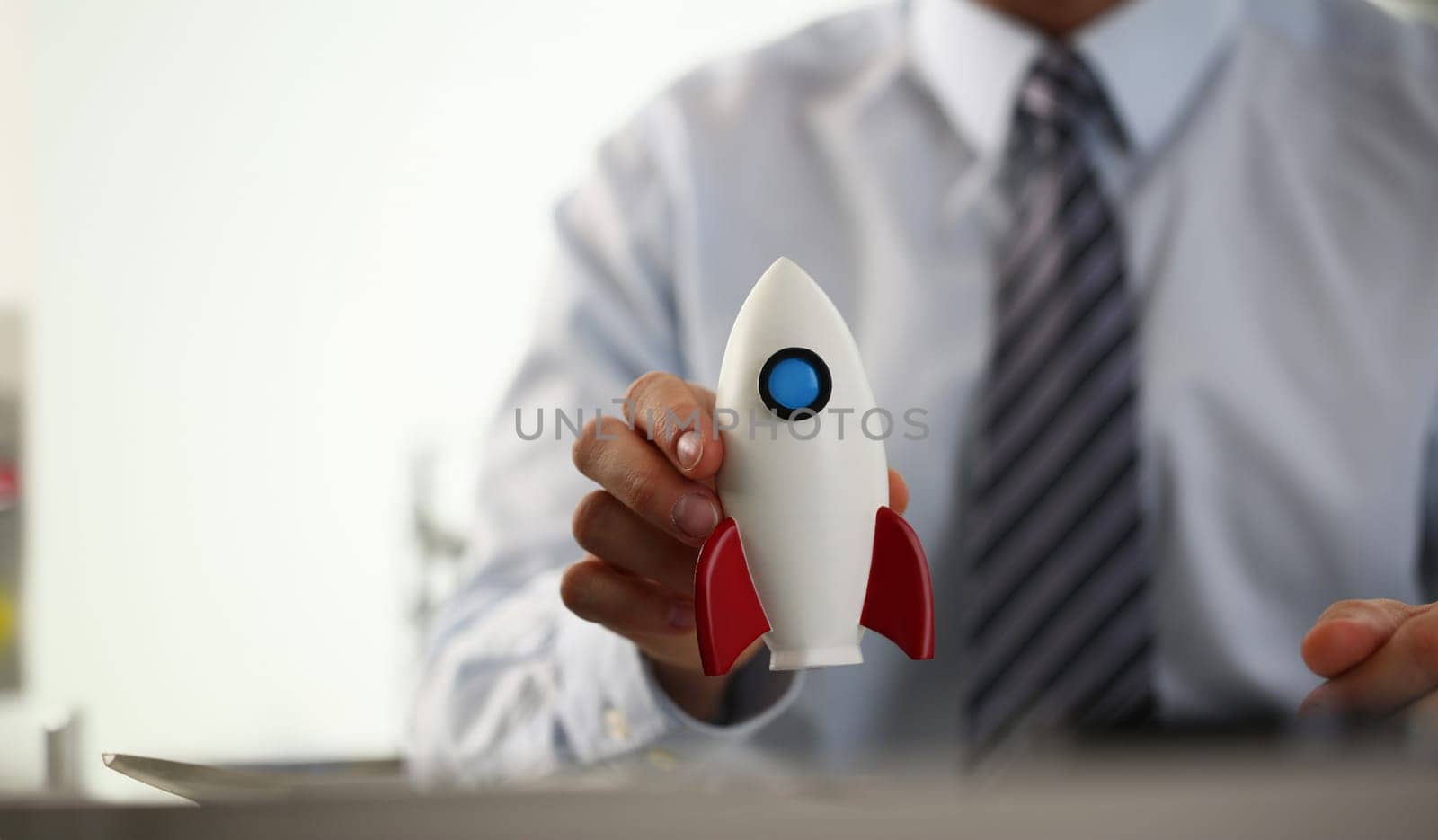 Businessman in suit hold white rockrt in hand office background