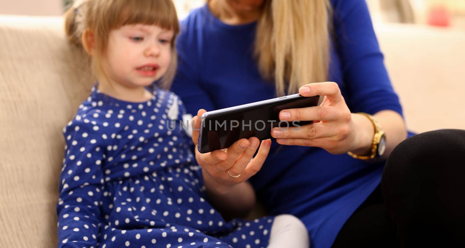 Cute little girl on floor carpet with mom use cellphone calling dad closeup. Life style apps social web network wireless ip telephony concept