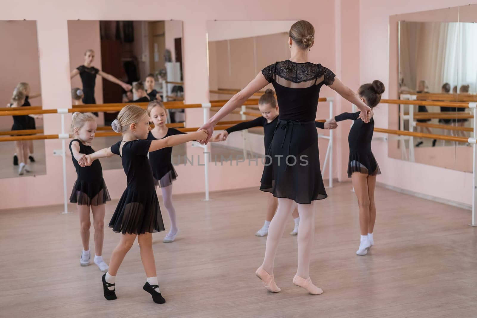 Children's ballet school. Caucasian woman teaching ballet to little girls