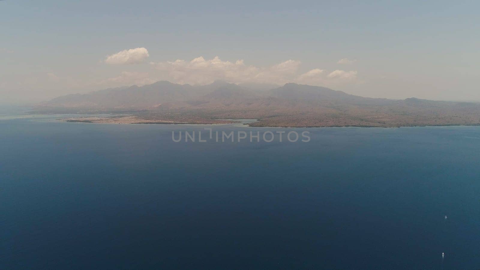 aerial coast of the island from the sea. seascape sea surface against mountains. Flying over the azure surface ocean. Travel concept