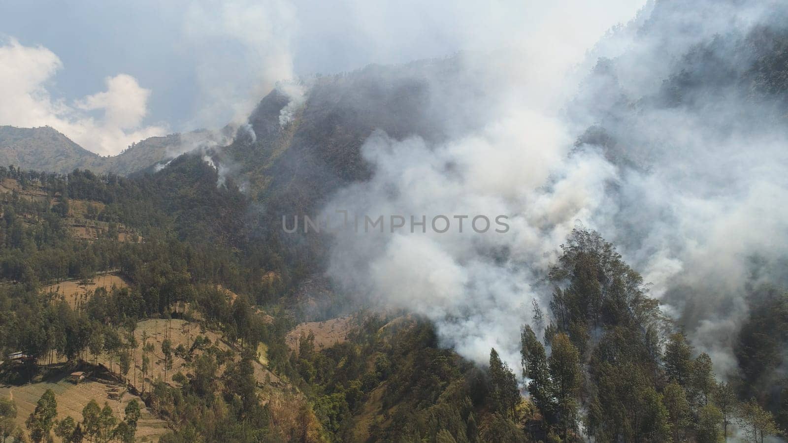 fire in mountain forest. aerial view forest fire and smoke on slopes hills. wild fire in mountains in tropical forest, Java Indonesia. natural disaster fire in Southeast Asia