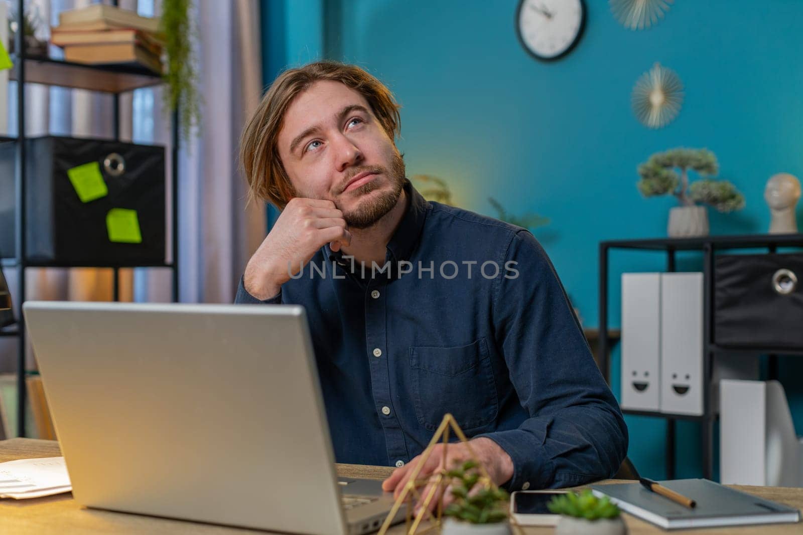 Thoughtful concerned businessman working on laptop computer looking away thinking solving problem at home office table. Serious freelancer search for inspiration make decision feel lack of ideas.