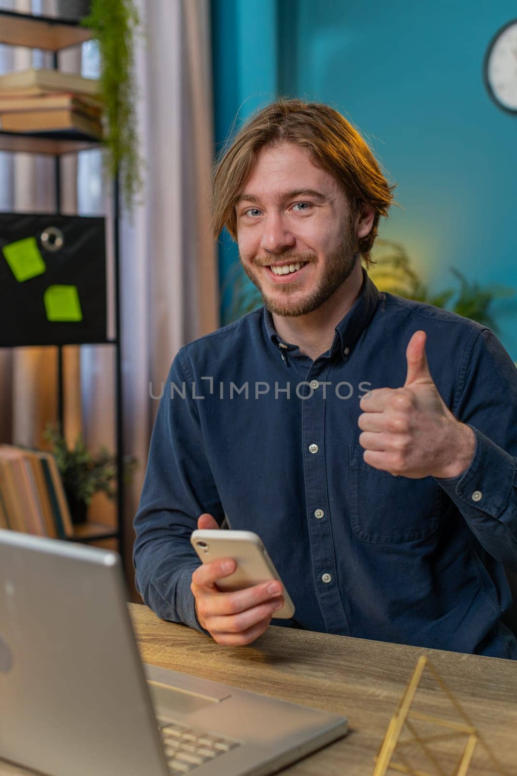 Businessman using smartphone app online pointing showing like thumbs up remote distance job working from home office. Man freelancer guy e-learning texting messages content on social media. Vertical