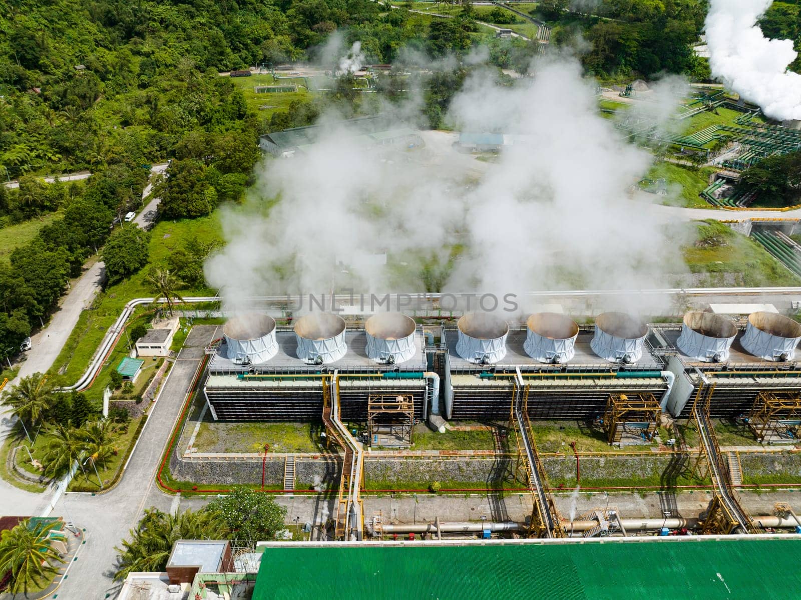 Geothermal power plant with smoking pipes and steam. Renewable energy production at a power station. Negros, Philippines.