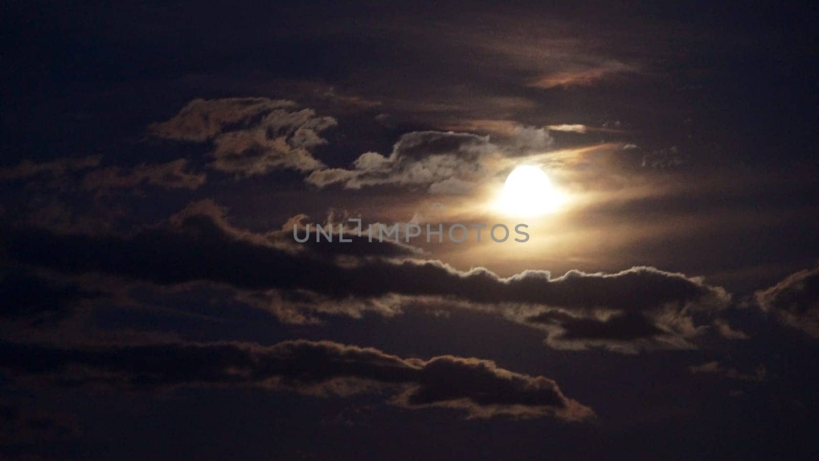 bright full moon illuminates the clouds in the night sky, dramatic sky.