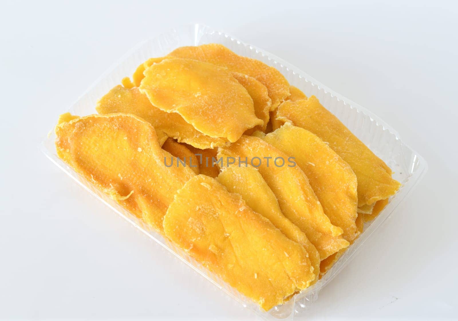 Dry mango in plastic container on a light background