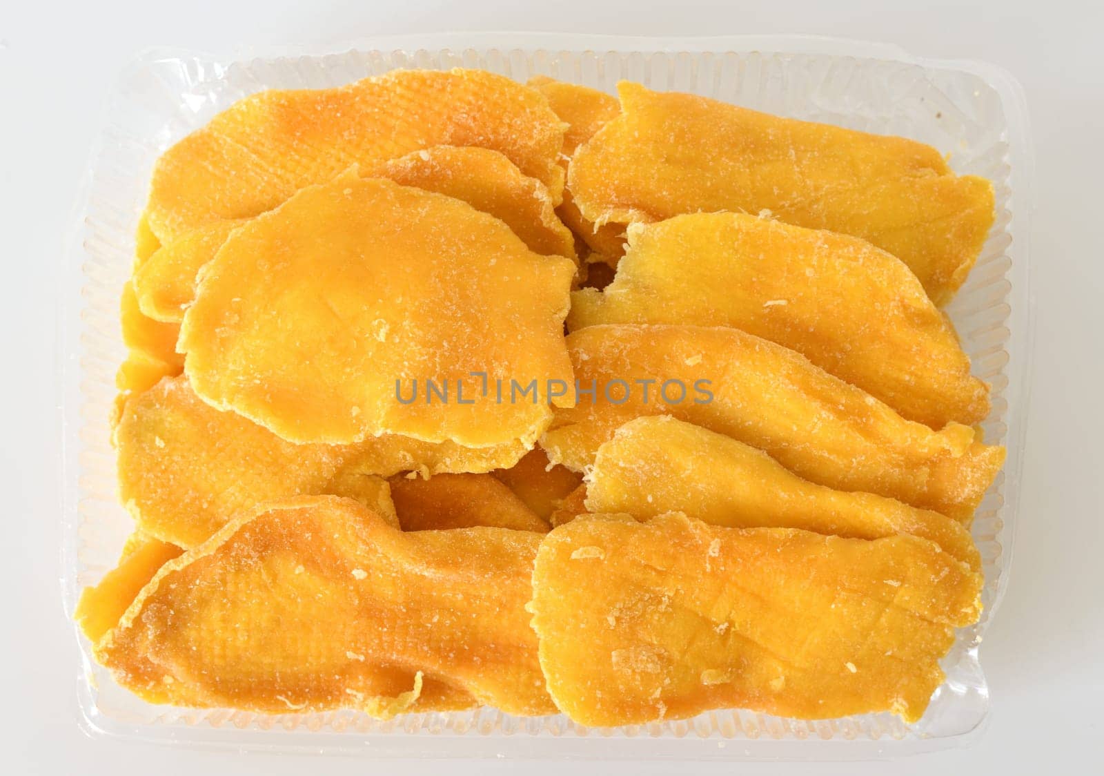 Dry mango in a plastic container on a light background by olgavolodina