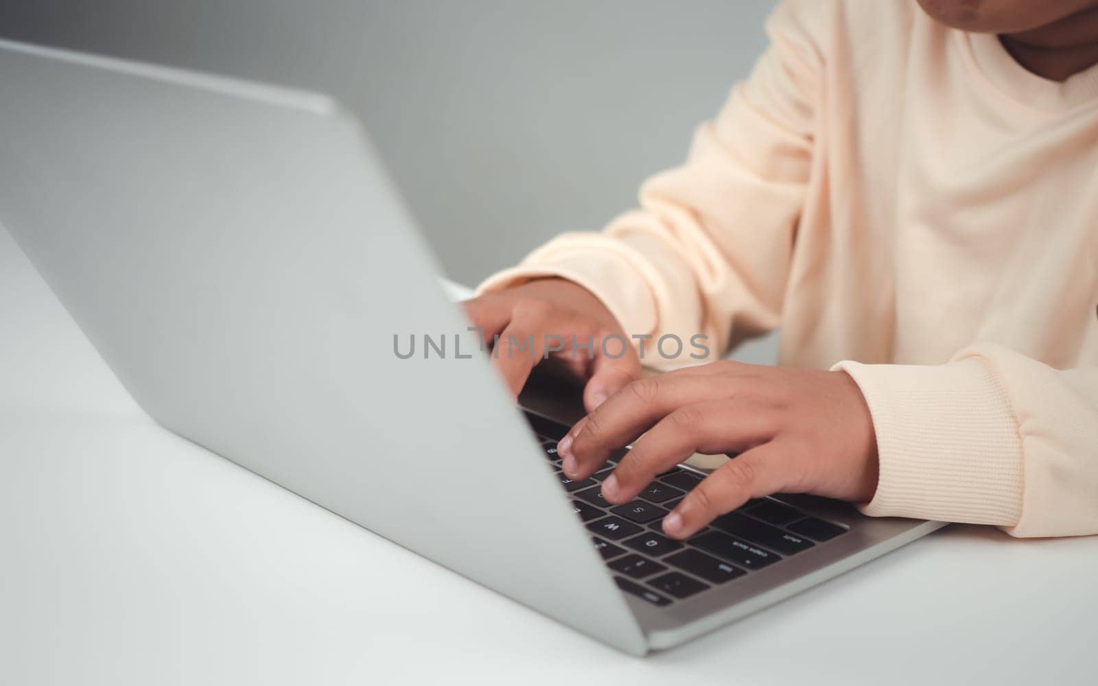Young businessman hand typing on laptop computer while working in white modern office room for business or technology background, Contact and communication in the organization. by Unimages2527