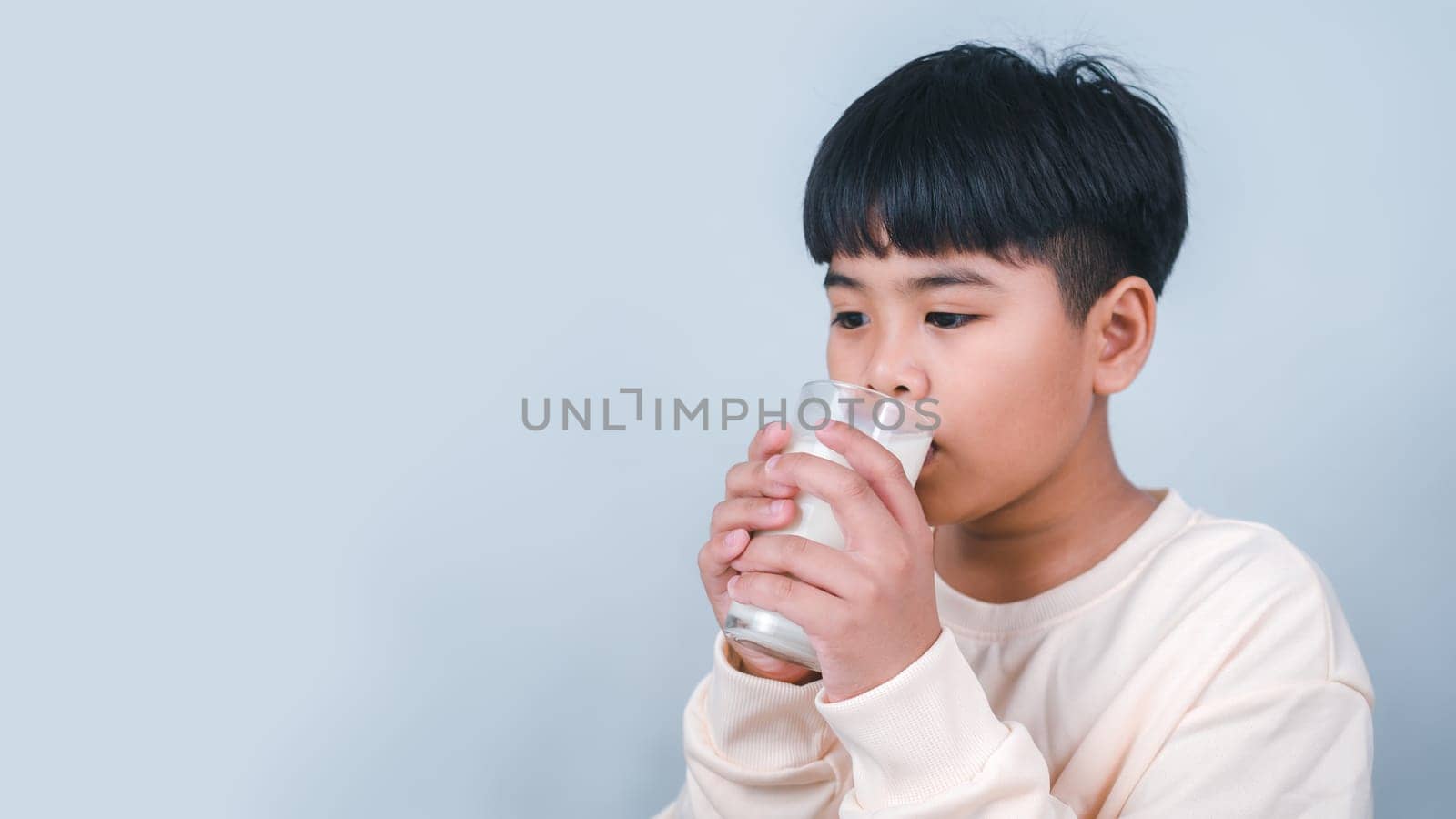 Concept of happy good nutrition, Portrait of a little young handsome kid boy in cream color shirt, Hold drinking milk box mockup, Isolated on white background.