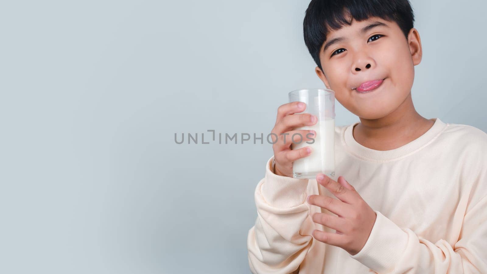 Concept of happy good nutrition, Portrait of a little young handsome kid boy in cream color shirt, Hold drinking milk box mockup, Isolated on white background. by Unimages2527