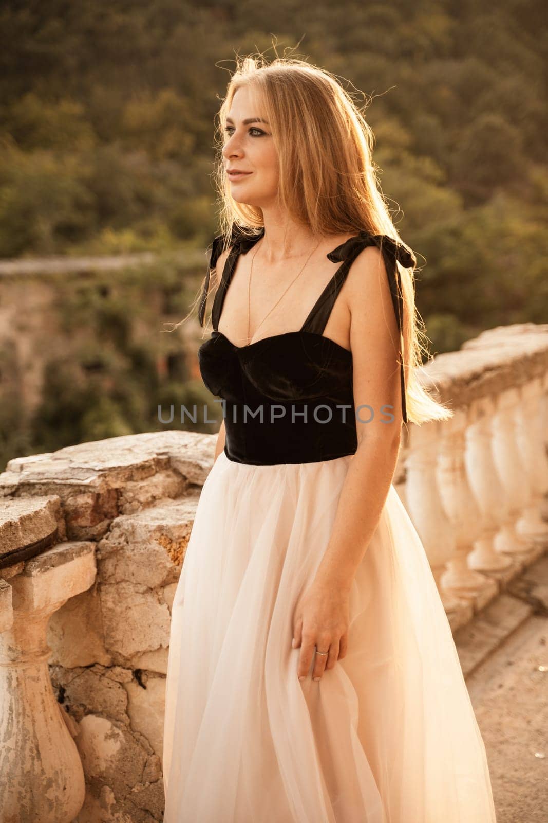 Blonde long hair, nature summer happy adult girl with long blond hair developing in the wind in nature. Dressed in a black top, white skirt. by Matiunina