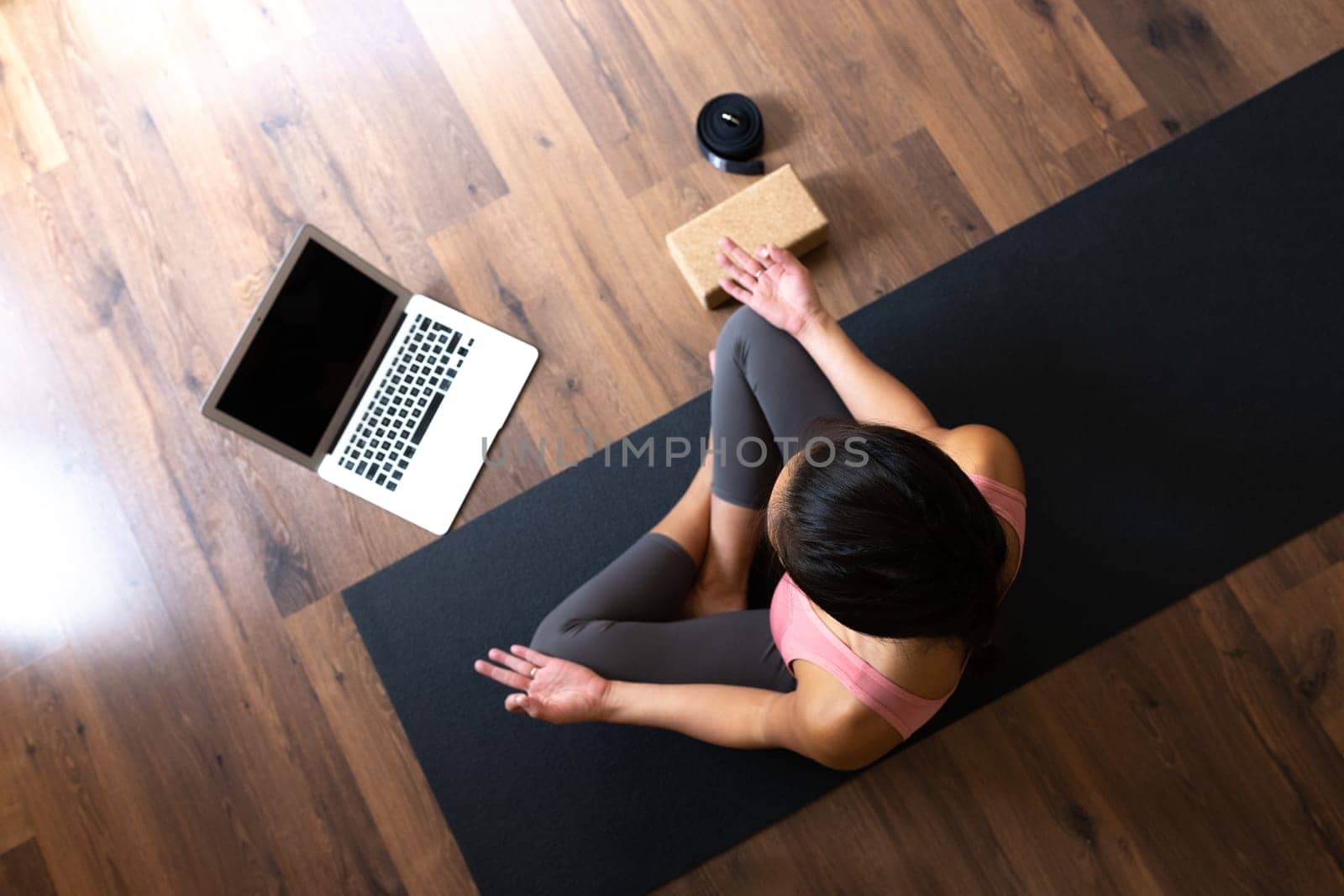 Top view of young woman wearing sports clothes doing online meditation and yoga class at home using laptop. Copy space. Healthy lifestyle concept.
