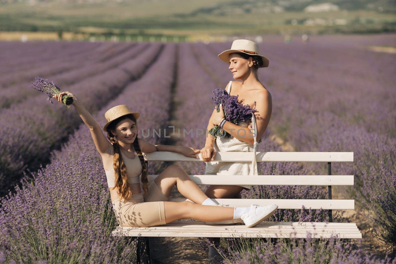 woman child sitting bench in field lavender. The woman is holding a bouquet of flowers, and the child is holding a bouquet as well. The scene is peaceful and serene