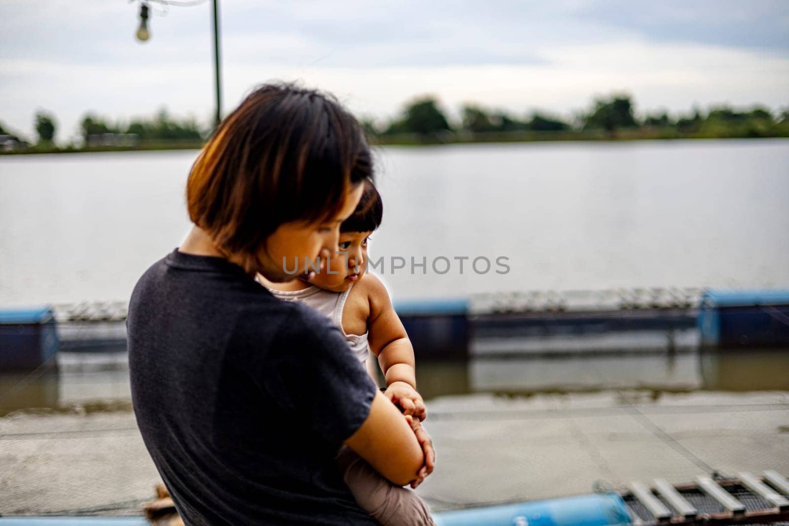 Mother and son watching fish in a pond of a fish farm. by urzine