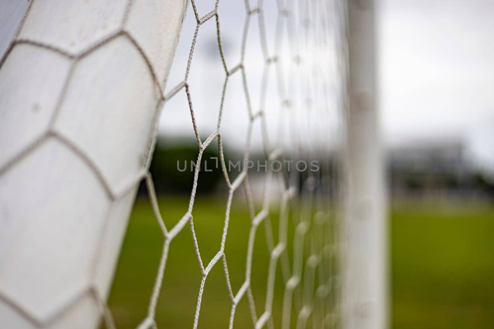 Soccer or football net background. View from behind the goal with blurred stadium and field pitch.