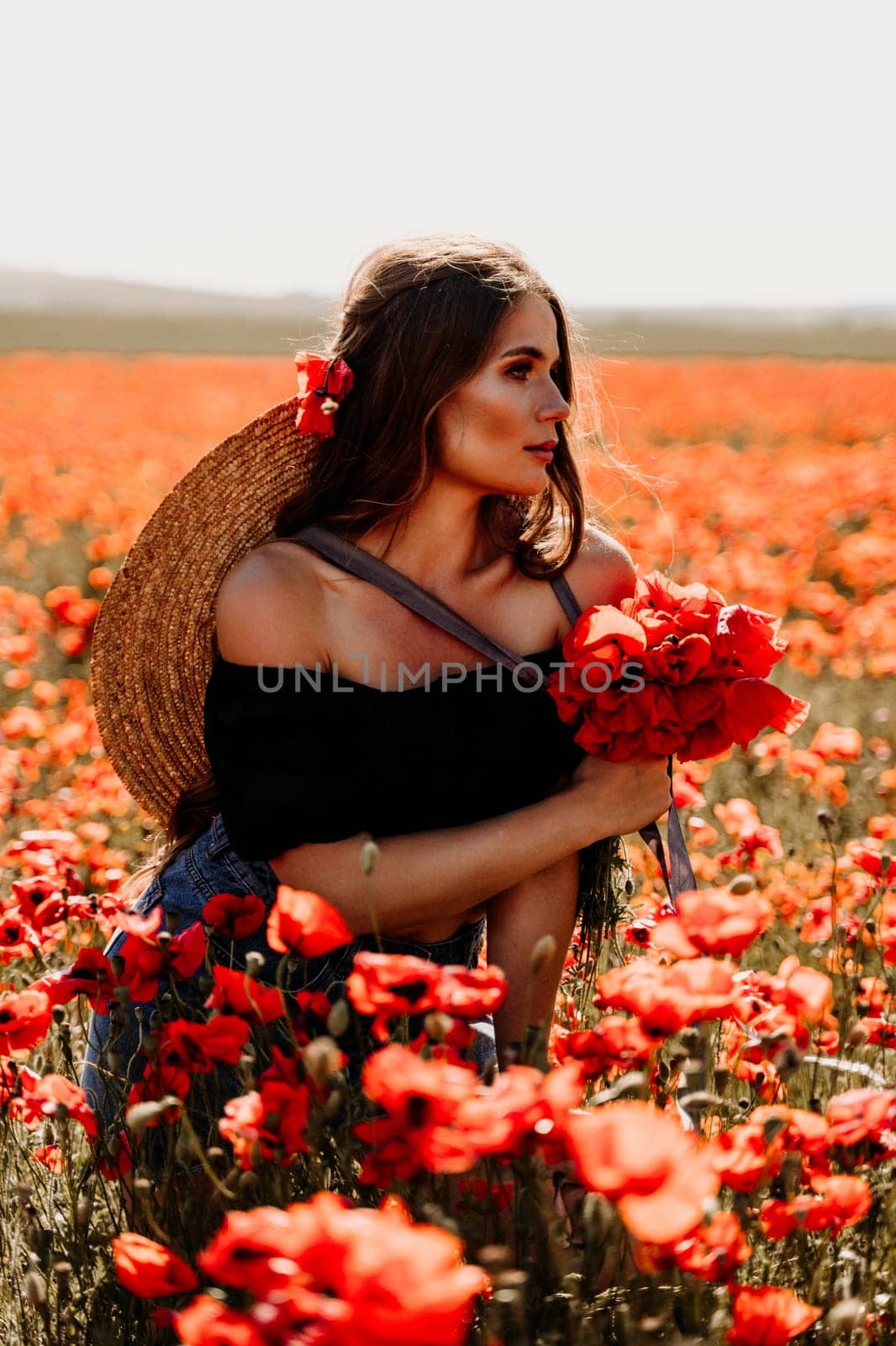 Woman poppies field. portrait of a happy woman with long hair in a poppy field and enjoying the beauty of nature in a warm summer day