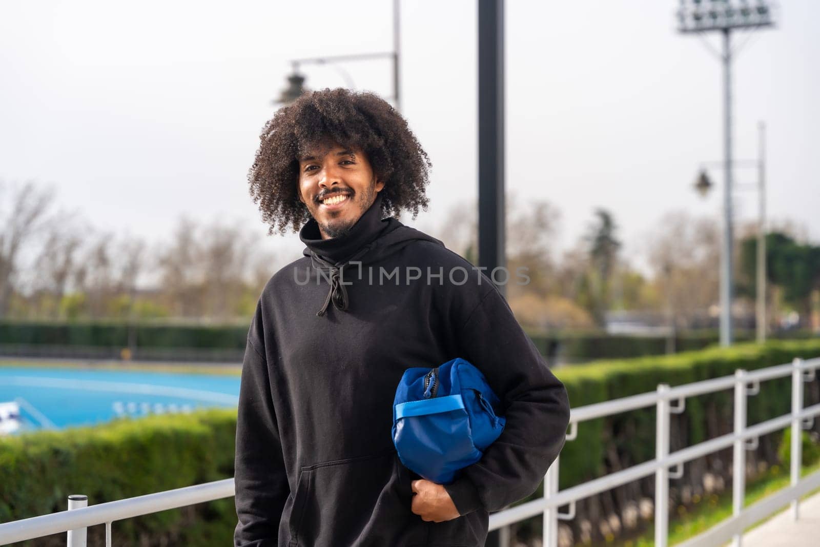 African man going to play pickleball carrying bag by Huizi