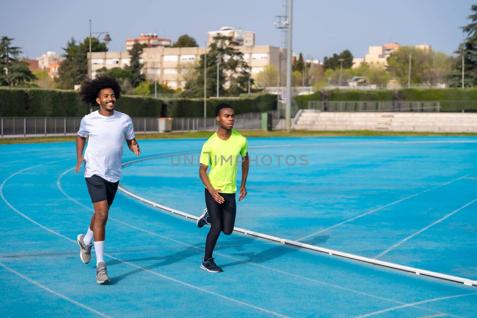 Sports men running together in an outdoor track by Huizi
