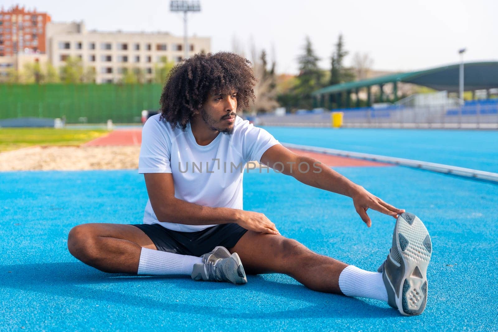 Man with african hairstyle stretching in a running track by Huizi