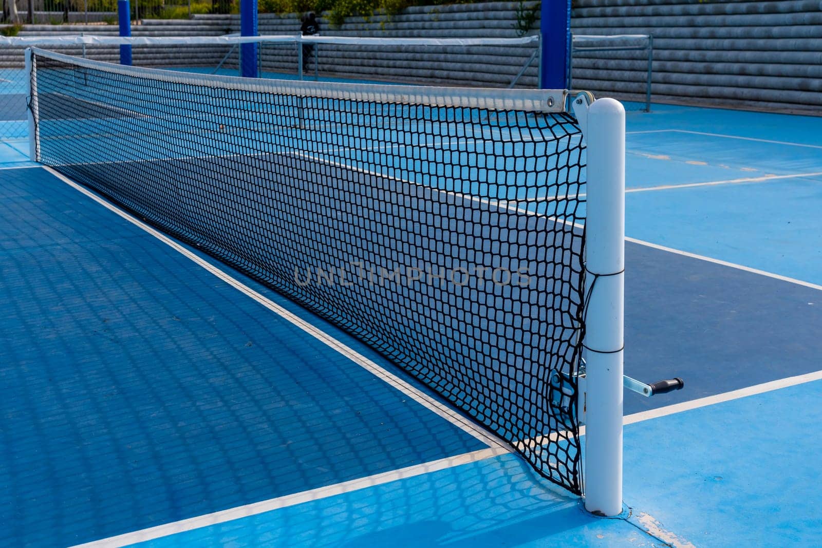 Pickleball net in a blue outdoor court wit no people by Huizi