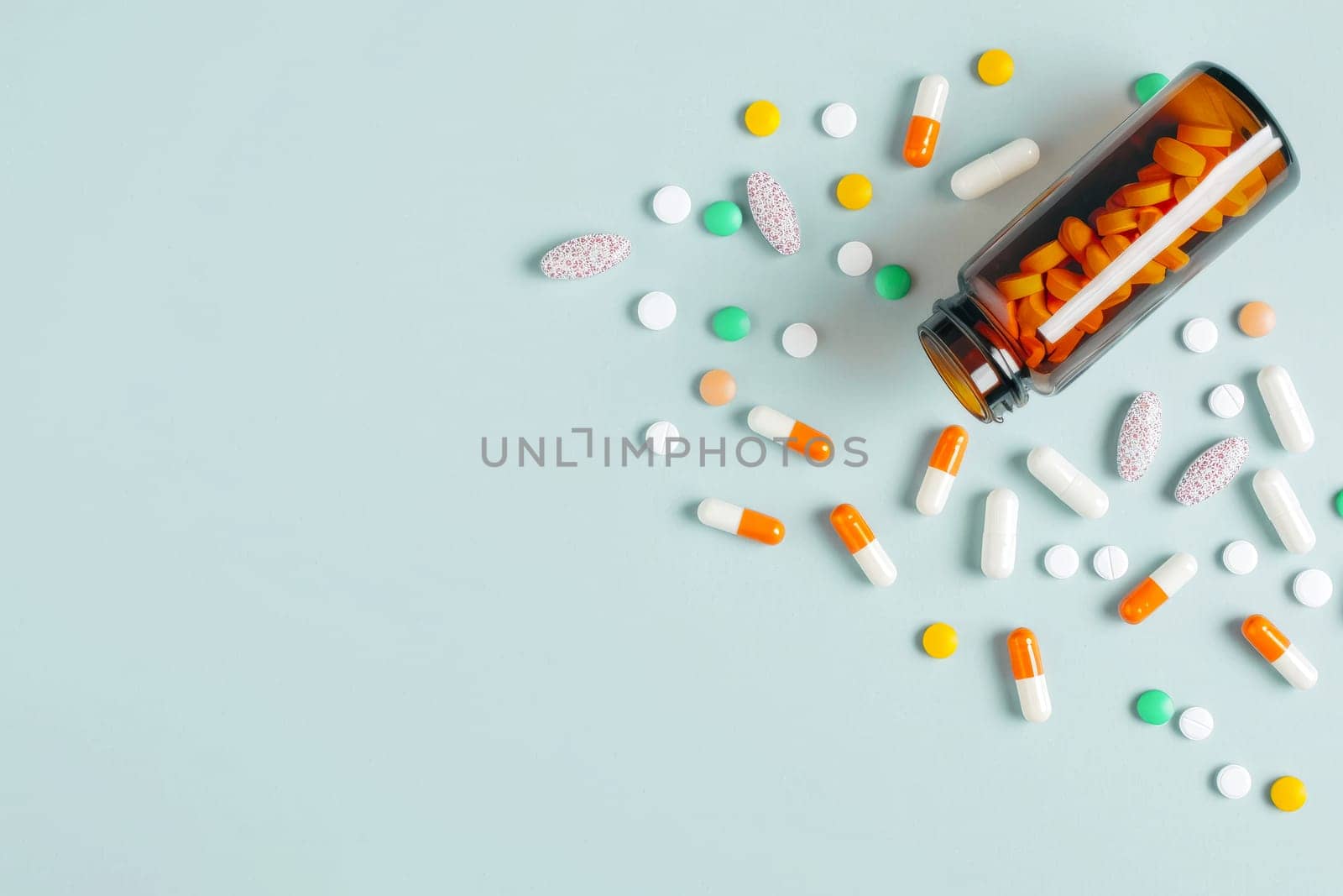 Medicine pills spilled from plastic pill bottle, on blue background. Medicine creative concepts. Flat lay top view, copy space by NataliPopova