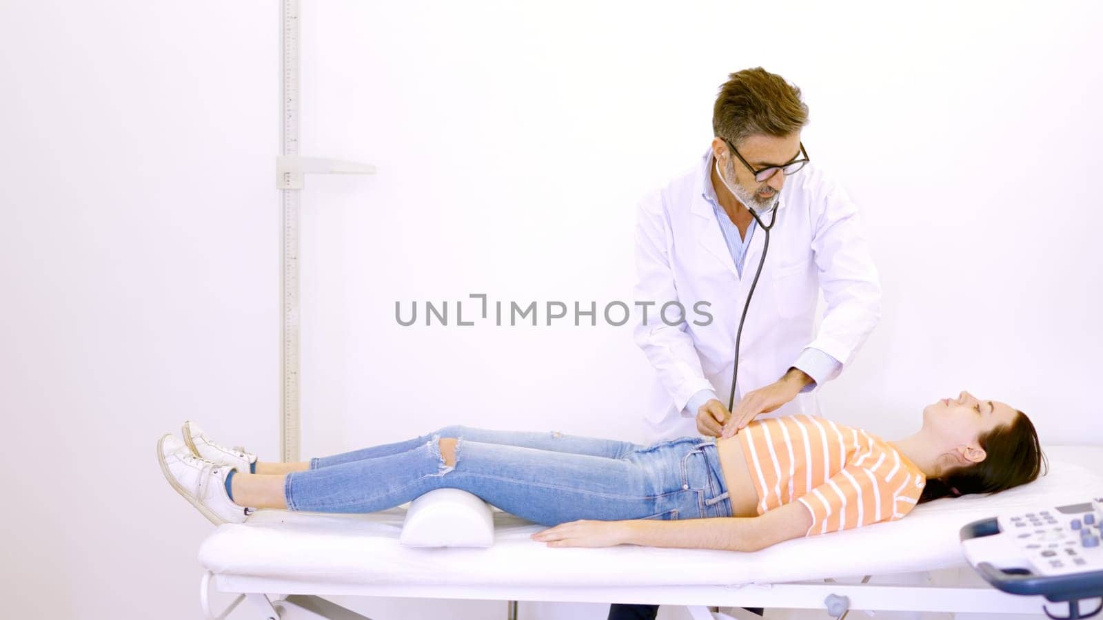 Doctor auscultating the patient's abdomen with a stethoscope by ivanmoreno