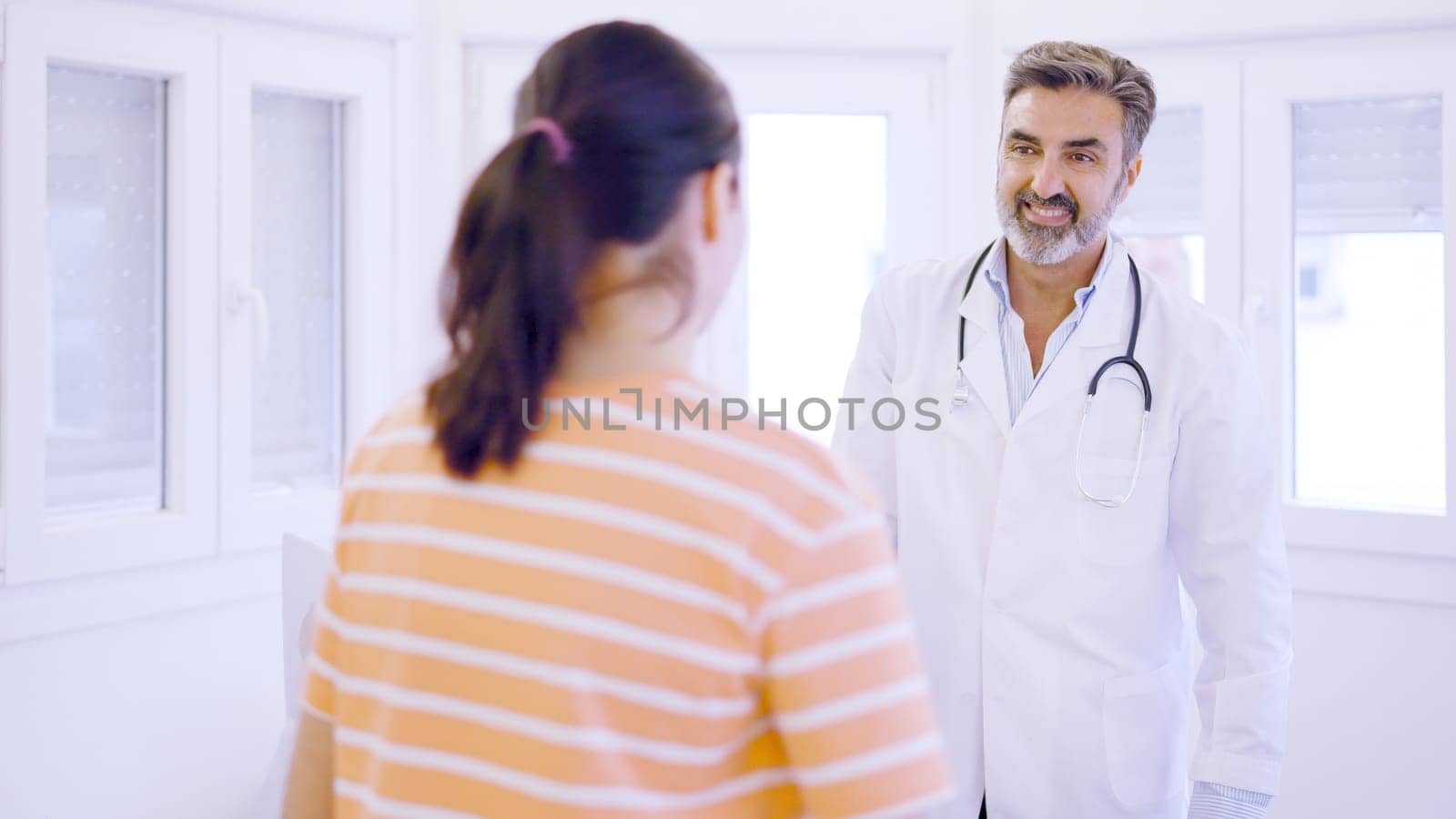 Female patient entering the consultation greeting the doctor in a medical clinic
