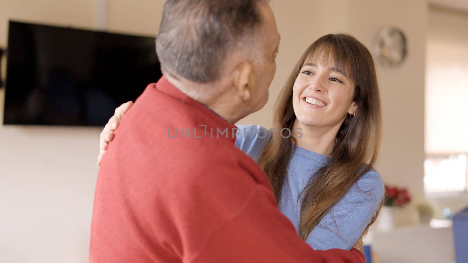 Happy grandfather receiving the visit of his granddaughter. They smile and talk