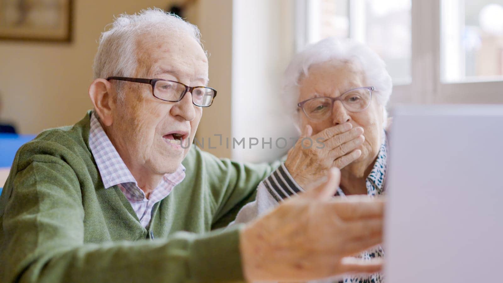 Grandparents enjoying a video call blowing kisses to his family by ivanmoreno