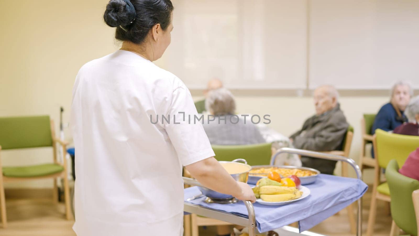 Female cook entering with food to the dining room of geriatric