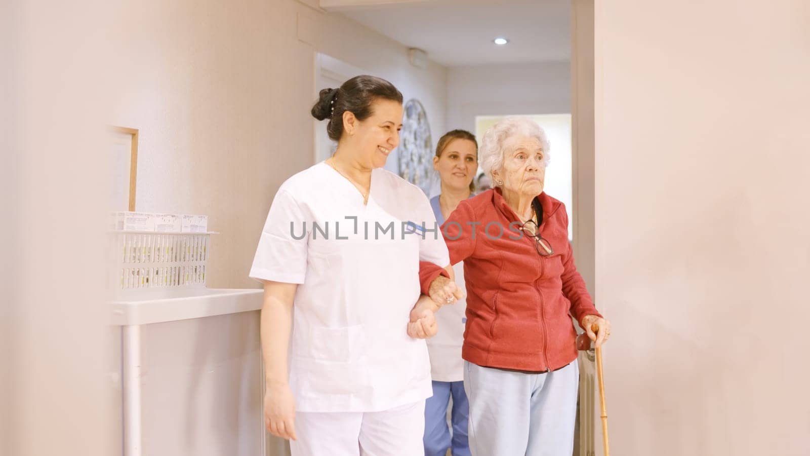 Caregivers holding arm of seniors while walking in a geriatric