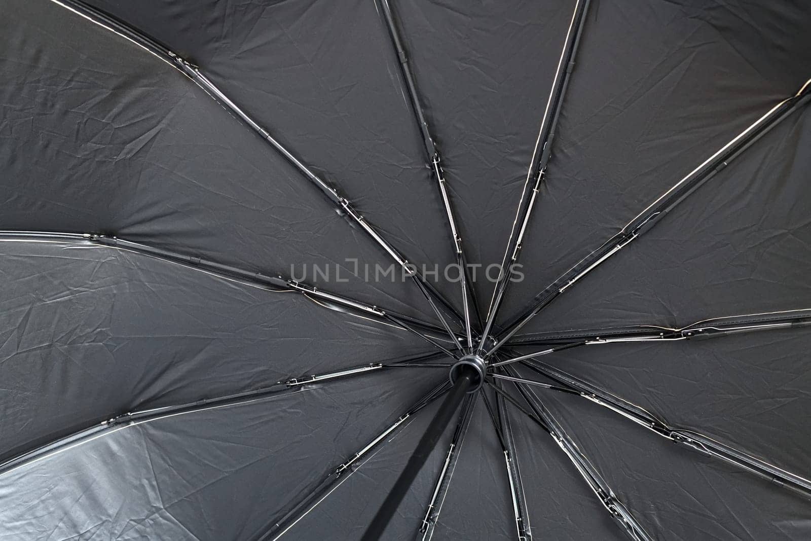 The inside of a black umbrella with spokes by olgavolodina