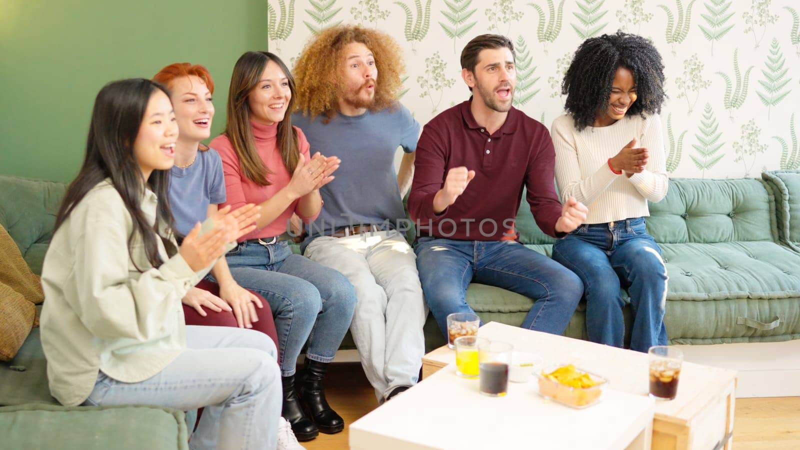 Group of friends celebrating something they are watching on TV by ivanmoreno