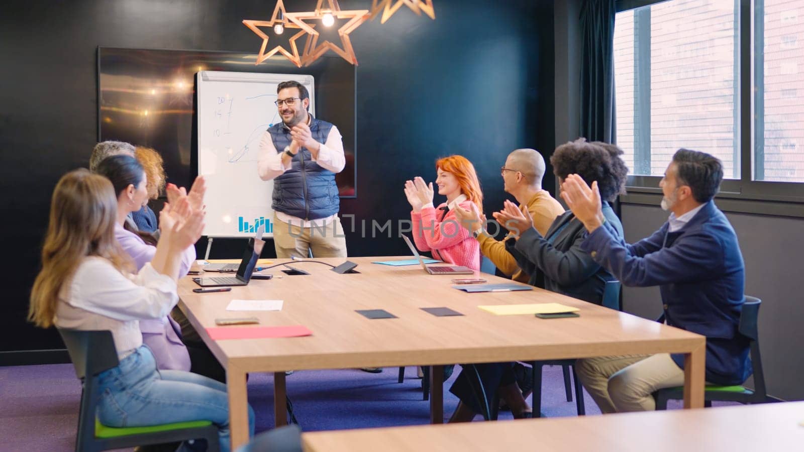 Group of multiracial coworkers congratulating a colleague applauding in a meeting room