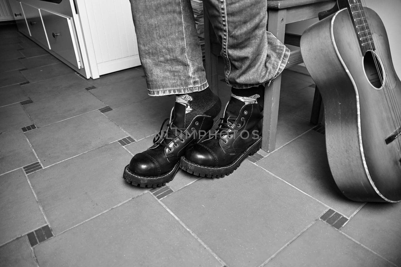 Rock and roll concept. Black boots and classic guitar. Black and white image.