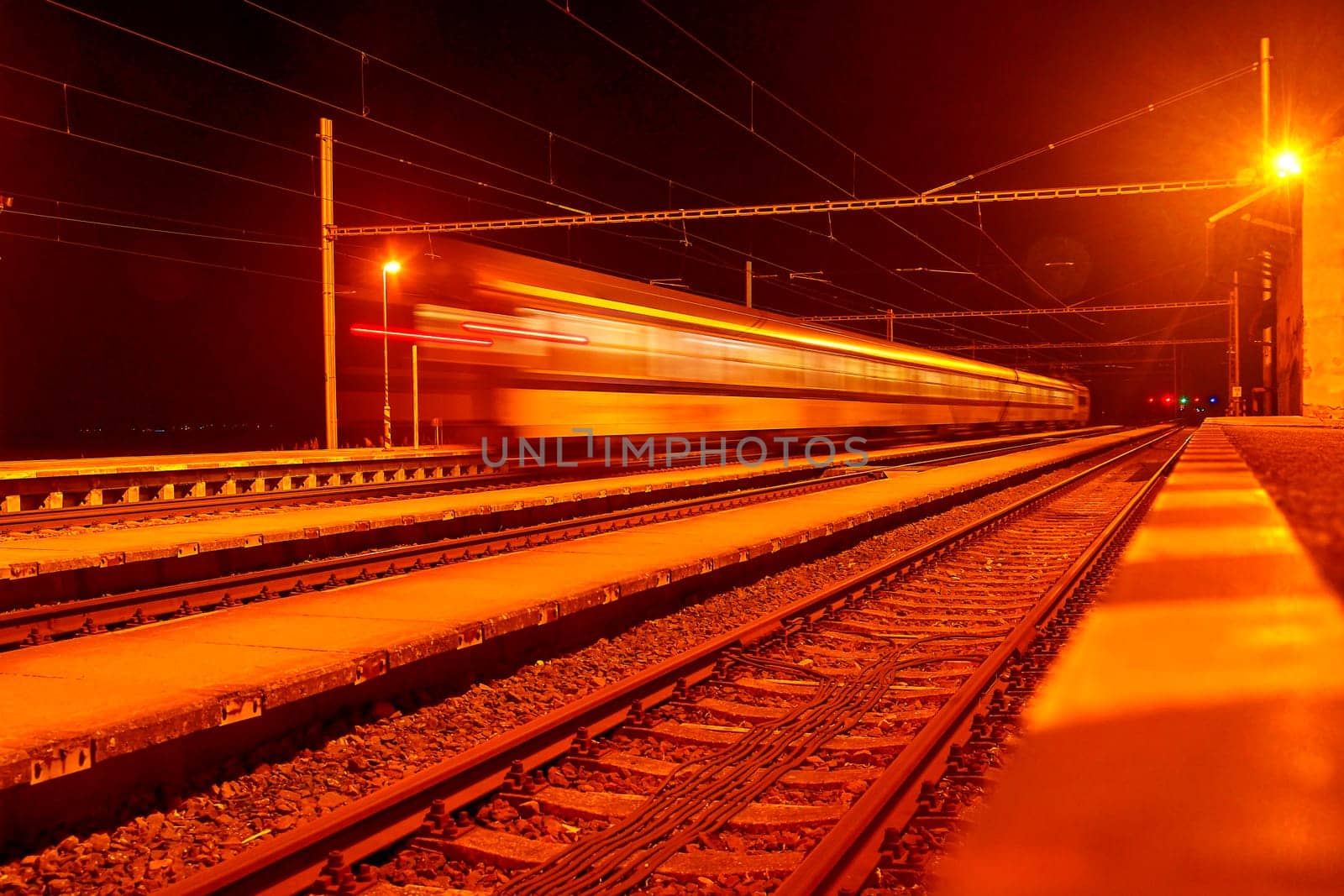 High speed passenger train on tracks with motion blur effect at night. Railway station in the Czech Republic by roman_nerud