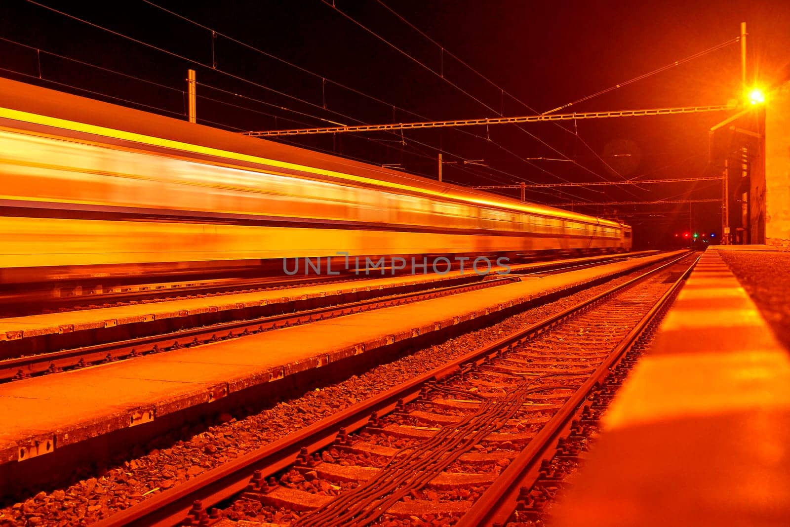 High speed passenger train on tracks with motion blur effect at night. Railway station in the Czech Republic.