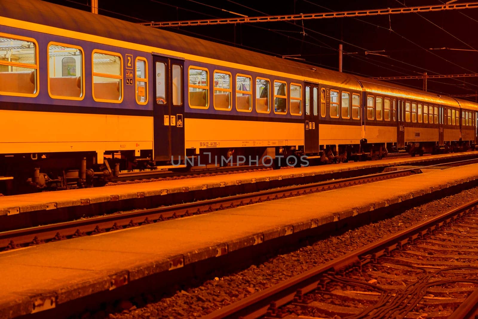 White and blue train standing at a small roofless train station at night in the Czech Republic. European train by roman_nerud