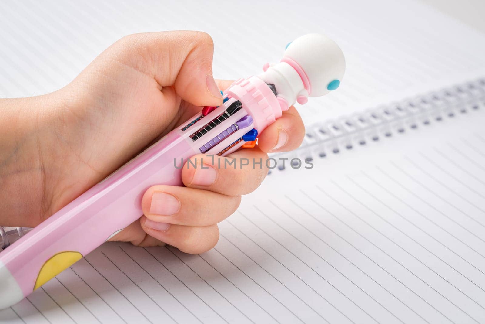 Little girl chooses color from a pen that can write in different colors