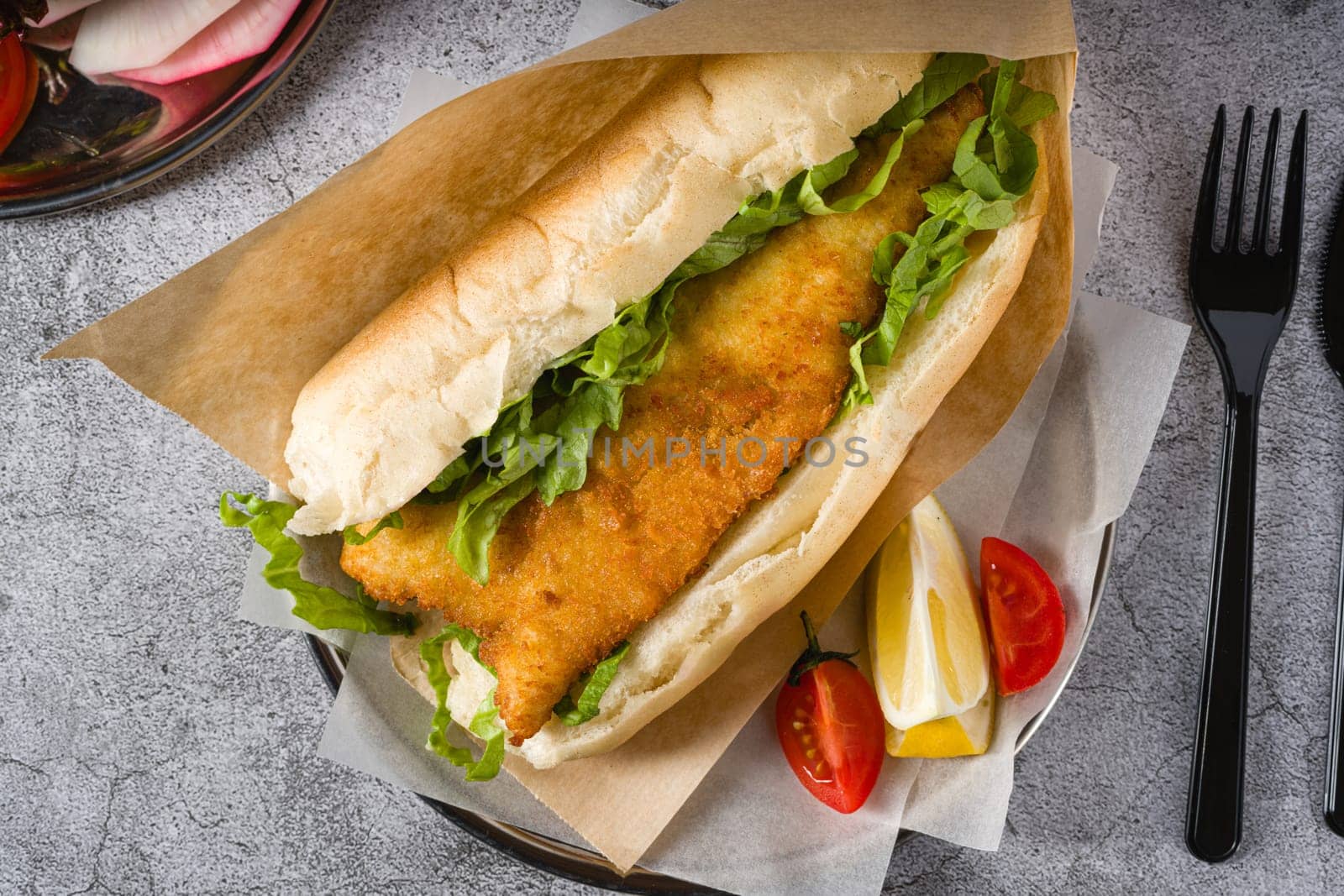 Fried fish sandwich with greens on the stone table. Turkish name Balik Ekmek