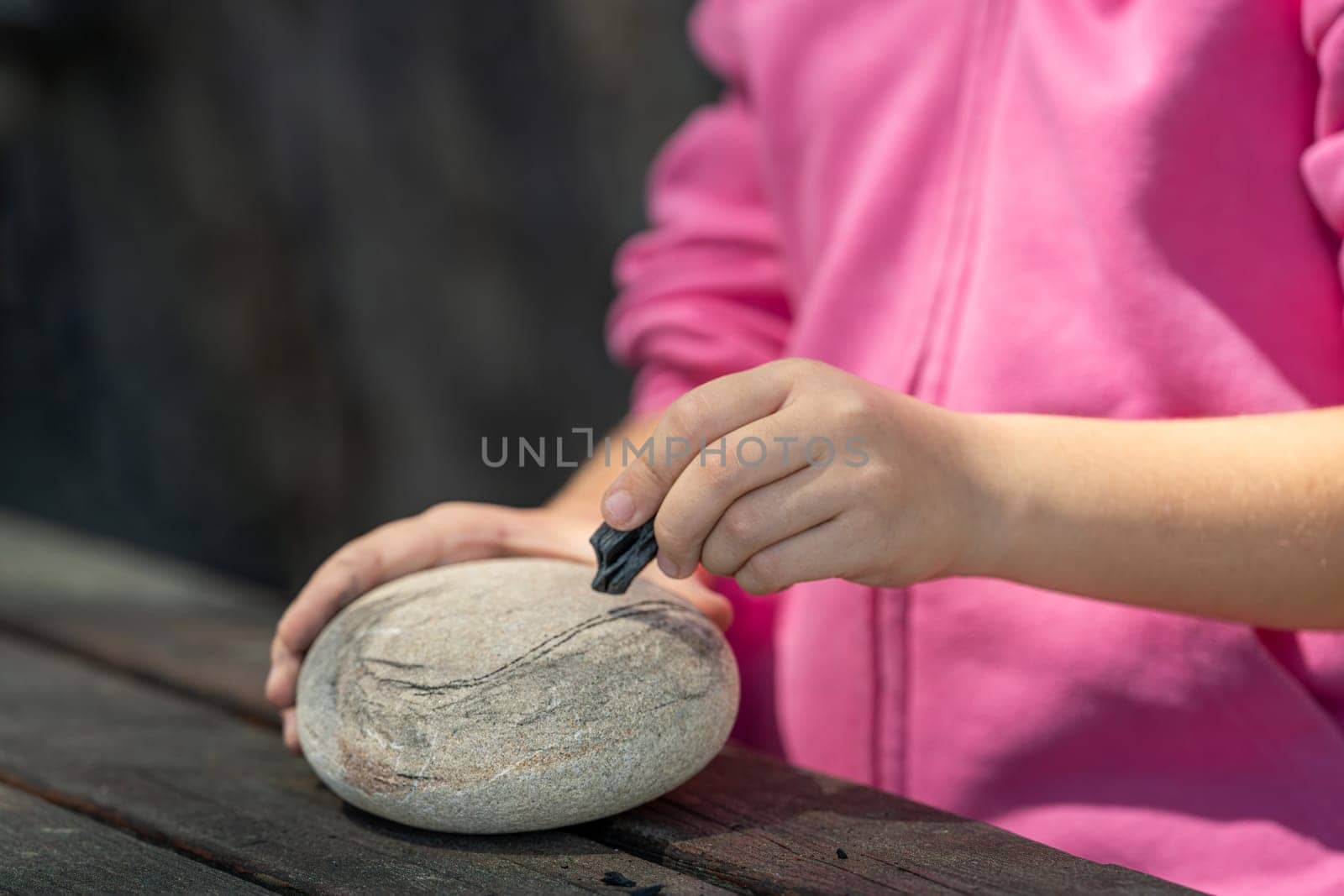 Girl drawing on a stone outdoors in the park by Sonat
