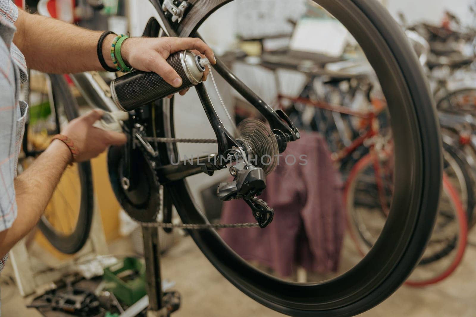 Close up of repairman is holding spray lubricant in his hand to lubricate the bike chain by Yaroslav_astakhov