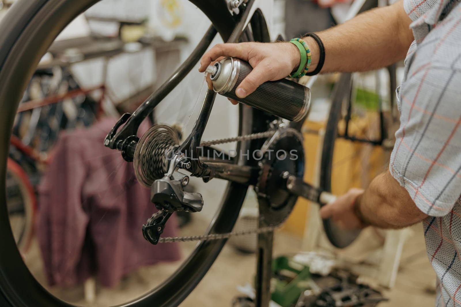 Close up of repairman is holding spray lubricant in his hand to lubricate the bike chain