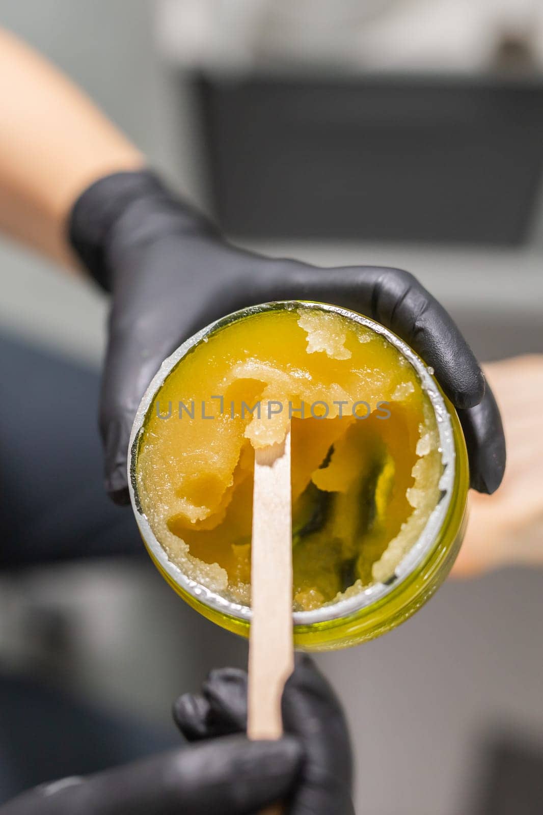 Orange body scrub with sugar and oil in glass jar in female hand. Homemade cosmetic for peeling and spa care. Copy space and empty place for advertising by Satura86