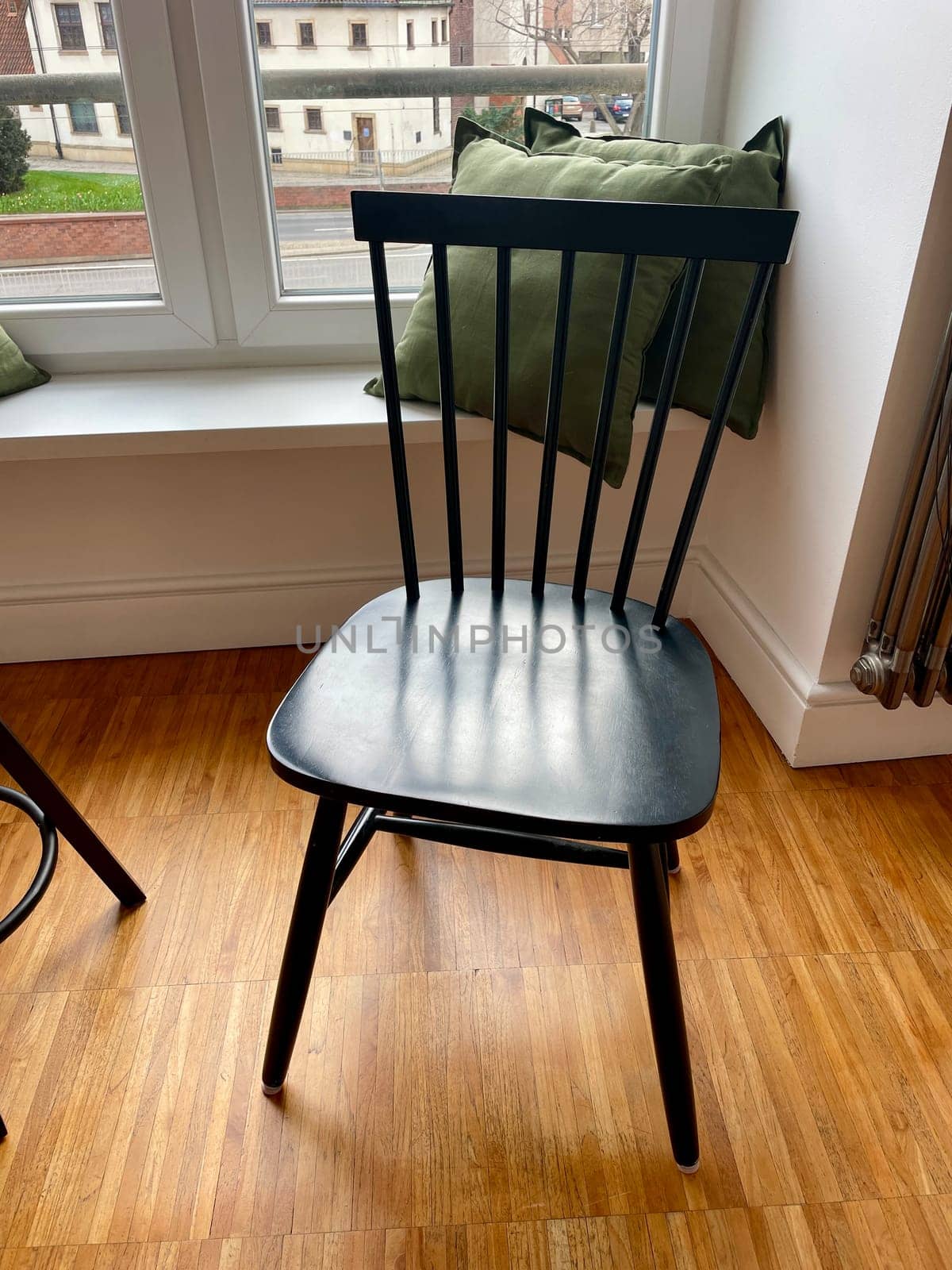 a wooden chair in front of a window with a view of the city, as part of the interior.