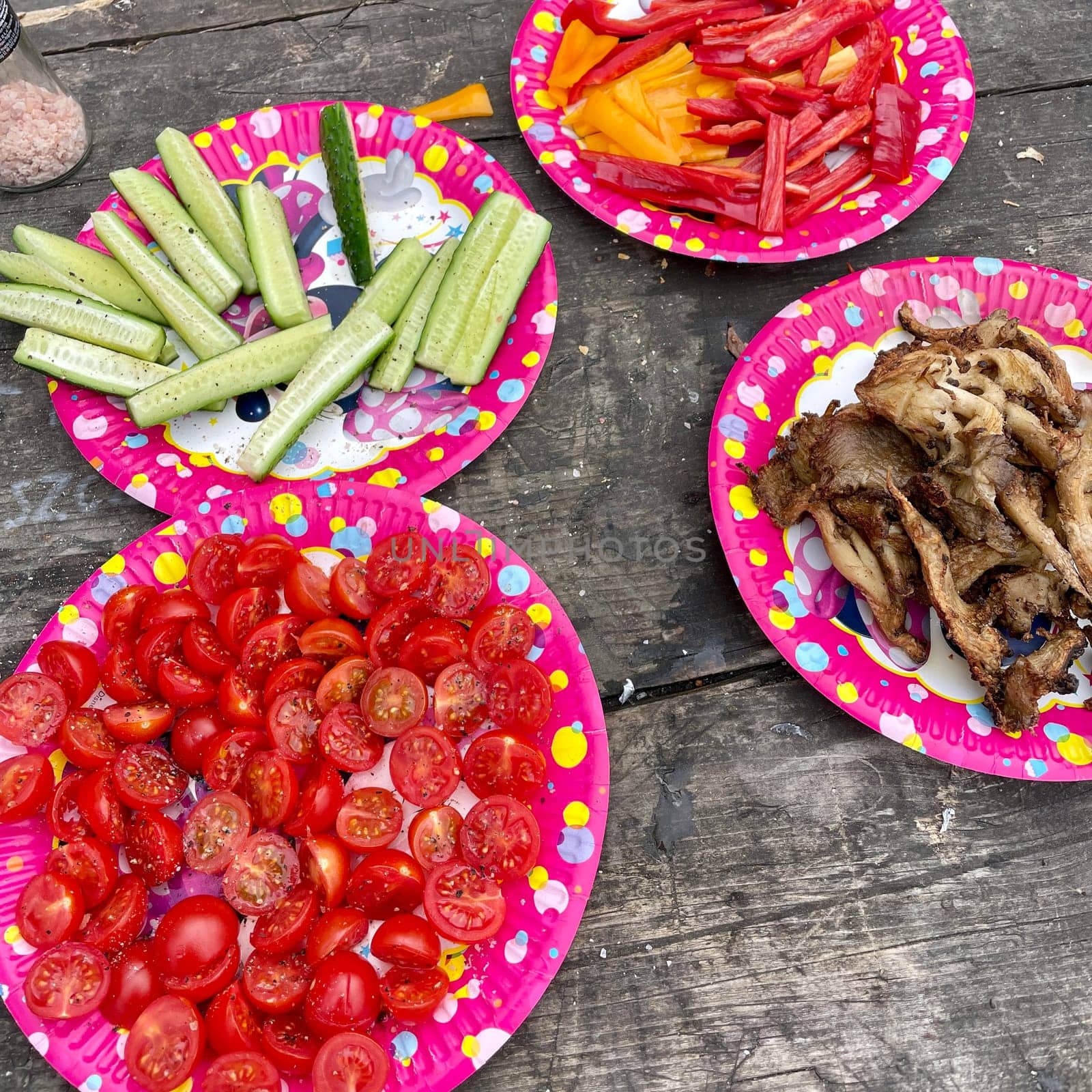 Colorful plates with vegetables and mushrooms on a wooden surface at a picnic. High quality photo