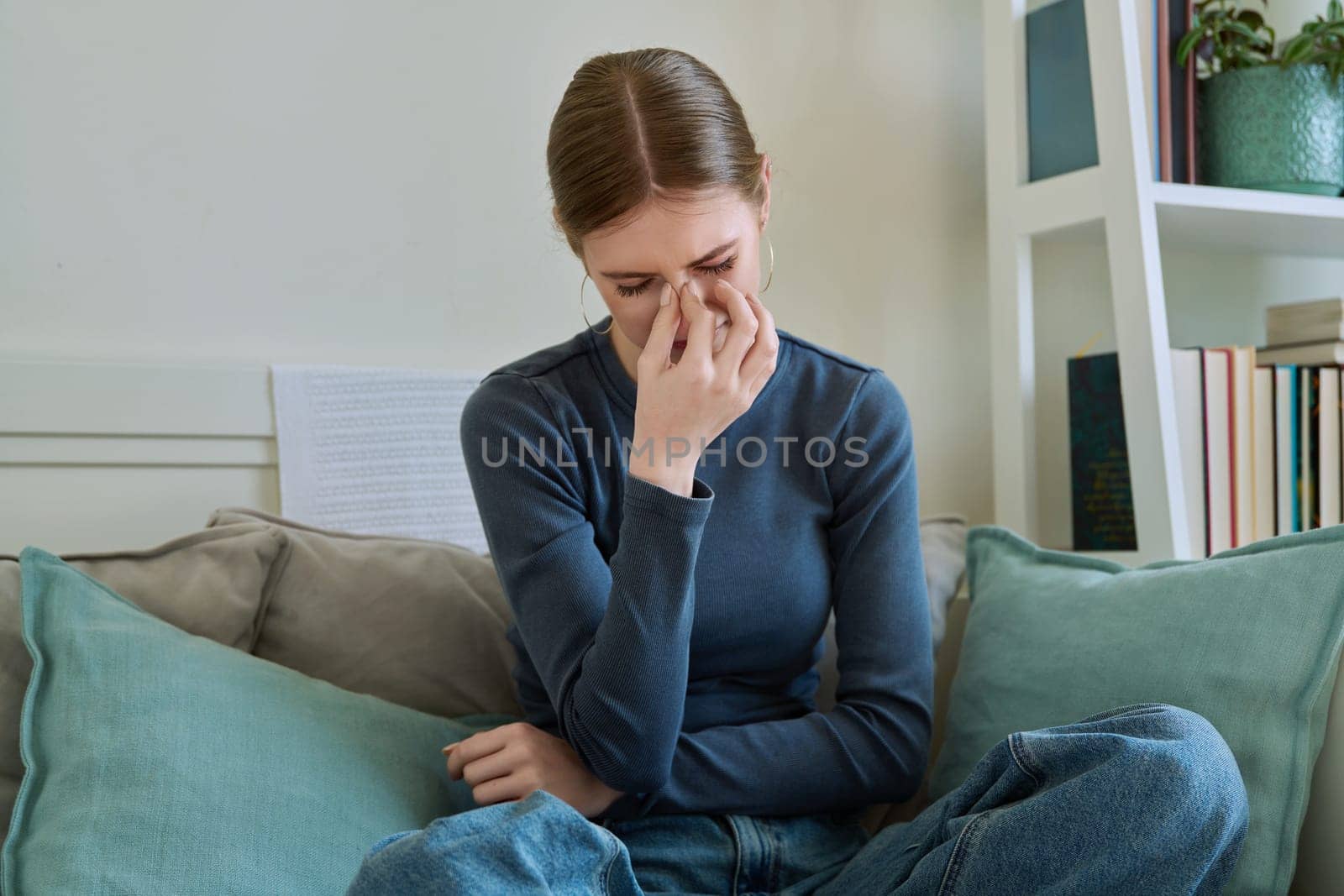 Young suffering female having headache, sitting on couch at home by VH-studio