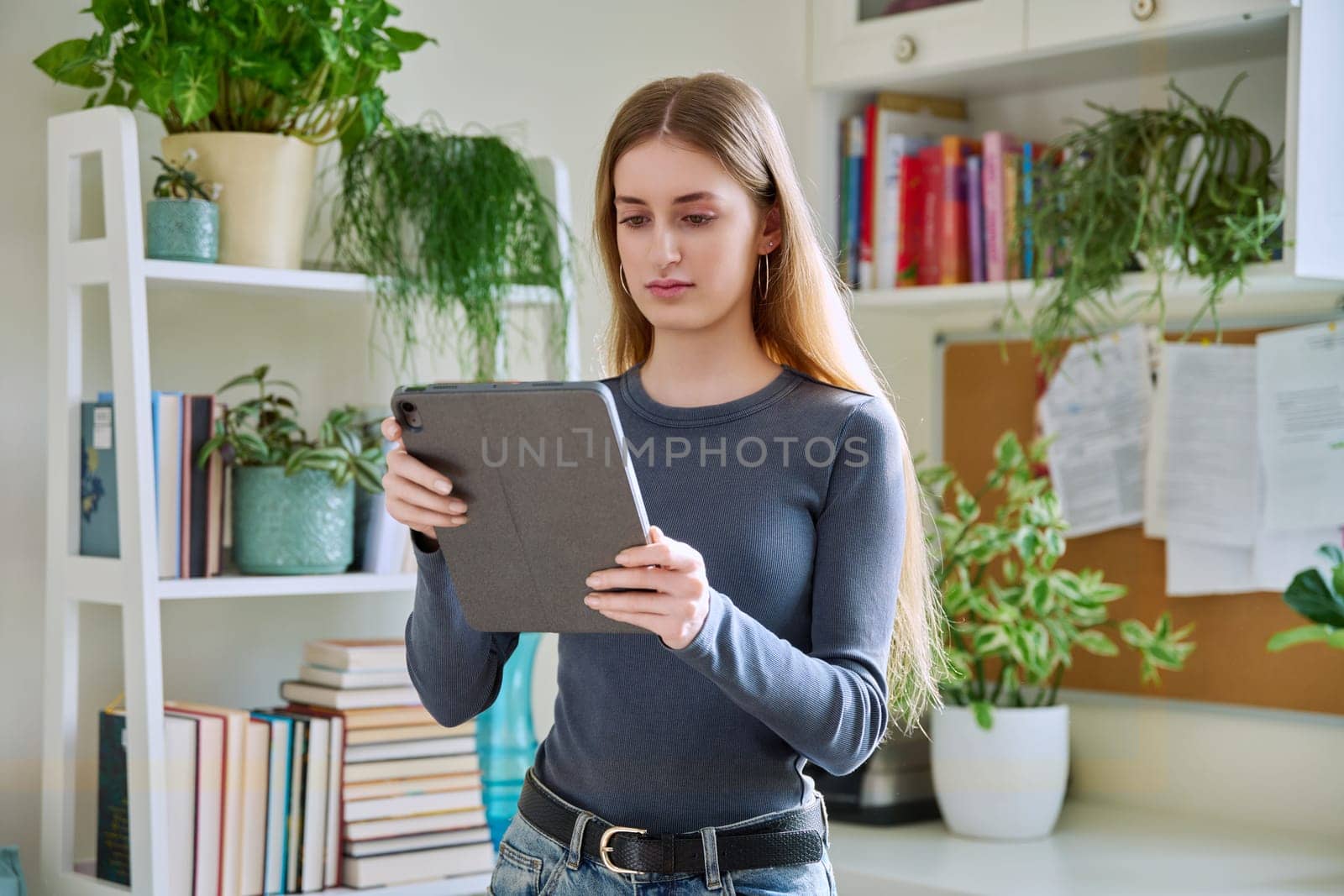 Young teenage female using digital tablet, home interior. Modern wireless technologies, Internet, online, apps applications, digital gadgets