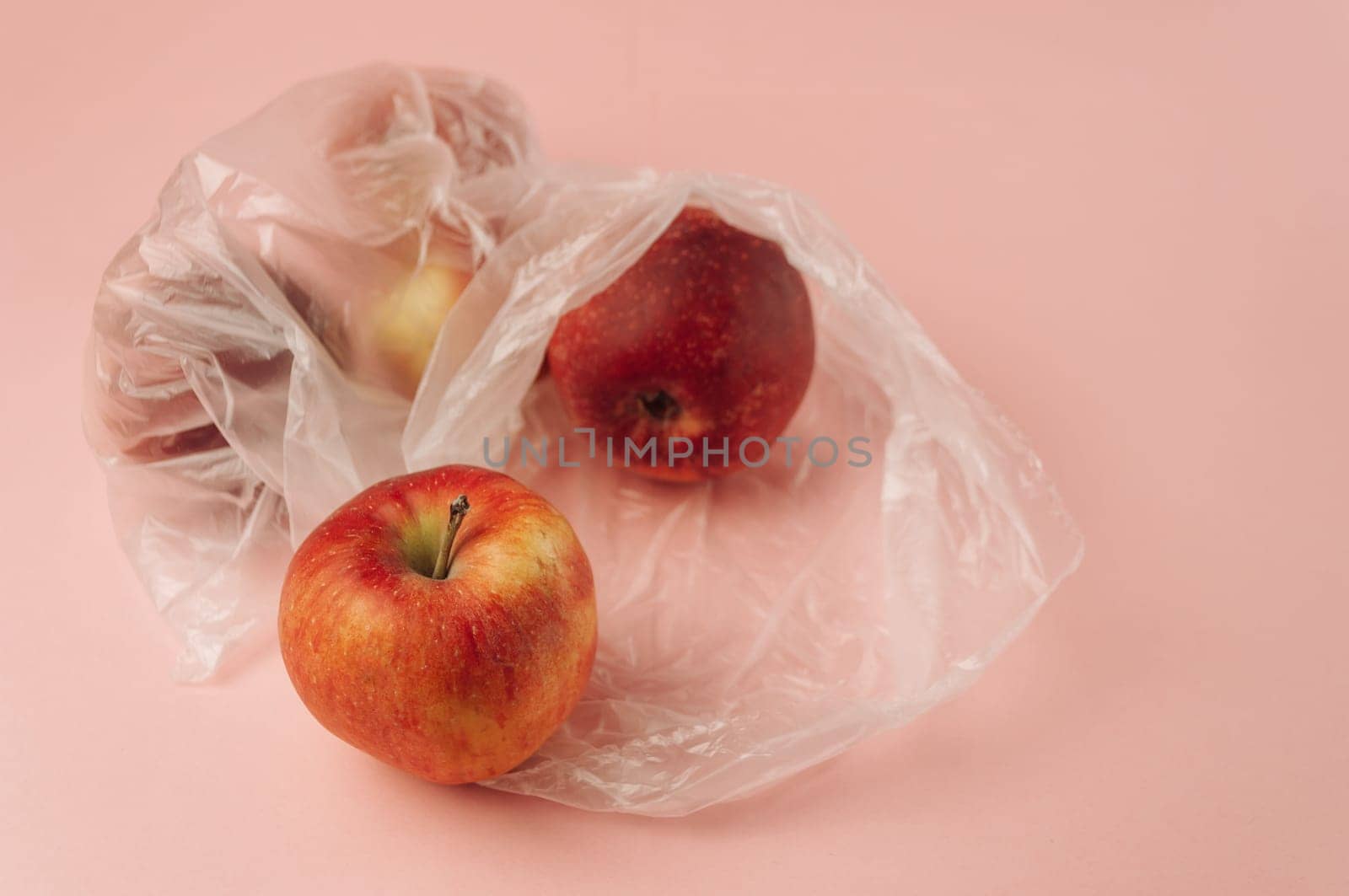 Three apples are in plastic bags on a pink background by Alla_Morozova93